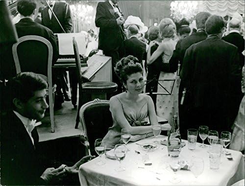 Foto vintage da princesa Soraya do Irã em uma festa, sentada, olhando para a câmera.